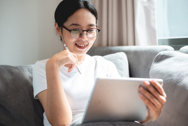 Young female business woman work at home with tablet or laptop computer, using online communication technology, asian people in happy lifestyle, beautiful girl person stay at home