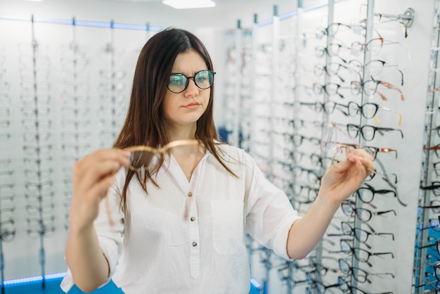 Young female buyer holds many glasses in hand