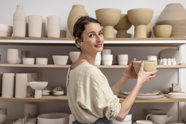 Foto giovane ceramista femminile che tiene in mano una concezione di prodotto in argilla fatta a mano di ceramiche