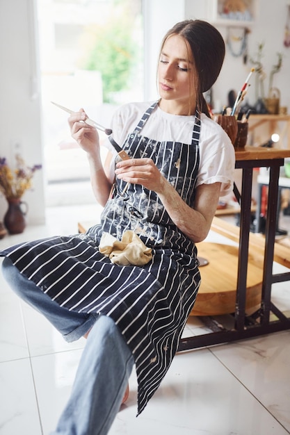 Photo young female ceramist indoors with handmade clay product conception of pottery