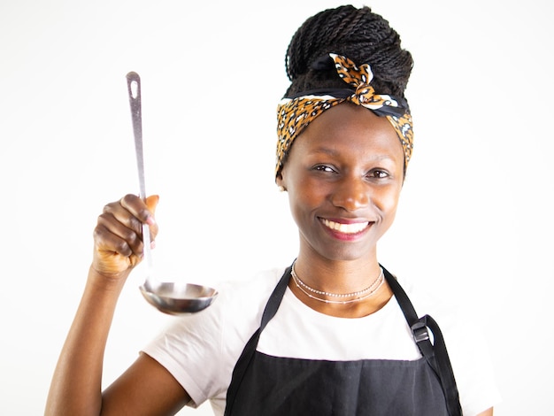 Young female chef showing a metal ladle while smiling and looking at camera Isolated on a white bac