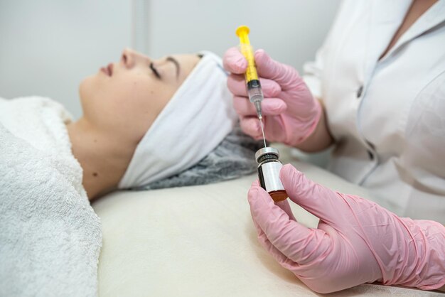 young female client receiving cosmetology treatment botox injection at spa clinic