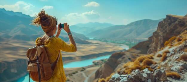 A young female climber stands on a cliff and takes pictures of the natural scenery with her phone