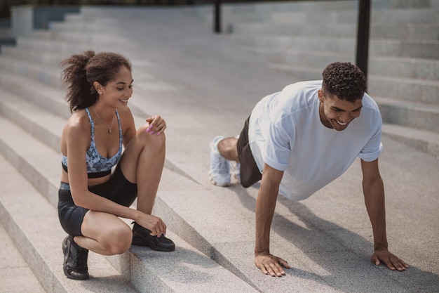 Young female coach training a young guy and looking involved