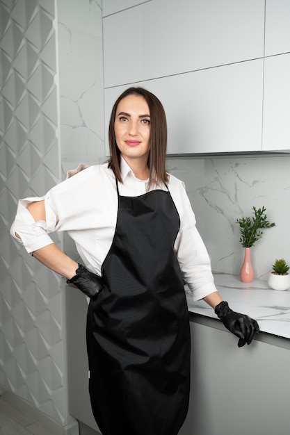 Young female confectioner in a black apron stand in the kitchen