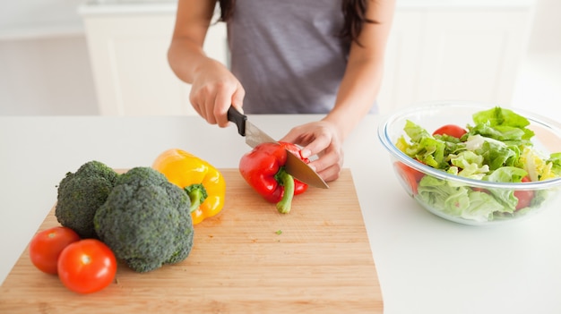 立っている間、若い女性の料理野菜