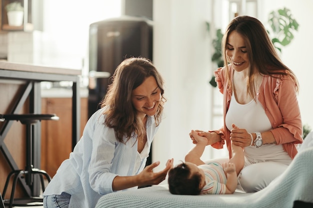 Young female couple enjoying while playing with their baby daughter at home