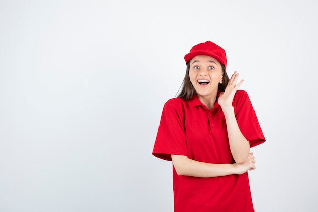 young female courier in red uniform feeling happy. 