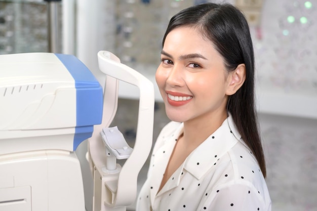 안과 의사가 자동 굴절 장치를 사용하여 시력 검사를 받는 젊은 여성 고객