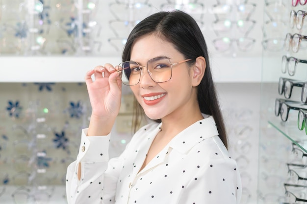 Young female customer choosing glasses in optical center Eyecare concept