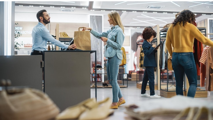 Photo young female customer shopping in clothing store retail sales associate helps with advice diverse people in fashionable shop choosing stylish clothes colorful brand with sustainable designs