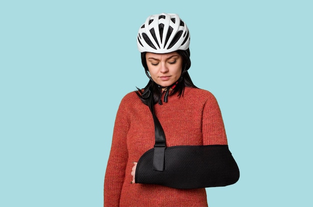 Photo young female cyclist with road injury wearing an arm sling shows discomfort or pain expression