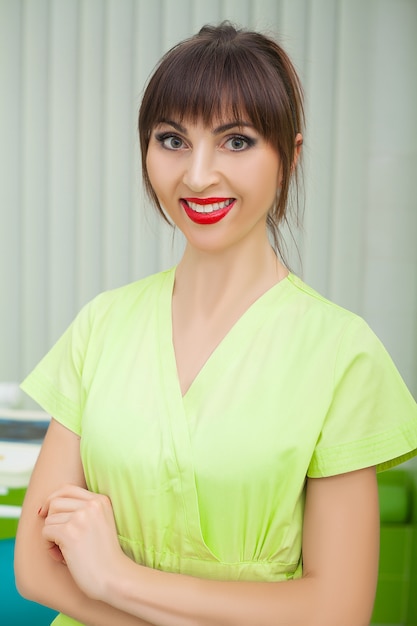 Young female dentist in green coat at workplace.