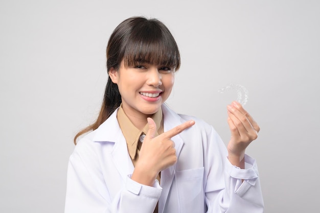 Young female dentist holding invisalign braces over white background