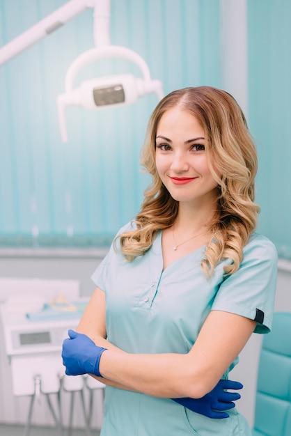 Young female dentist in workplace looks into camera