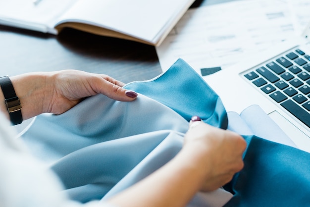 Young female designer comparing two textile samples while choosing more suitable one for new fashion collection