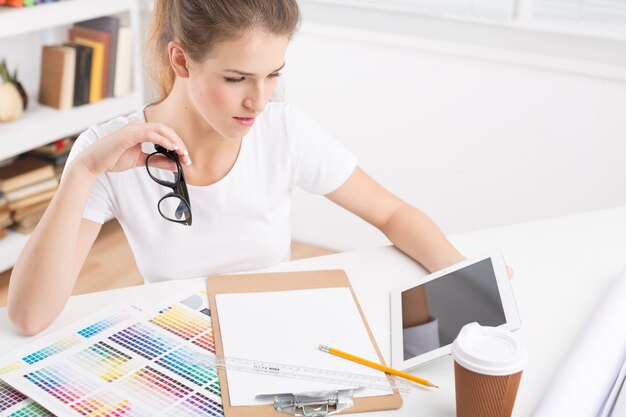 Young female designer with tablet at workplace