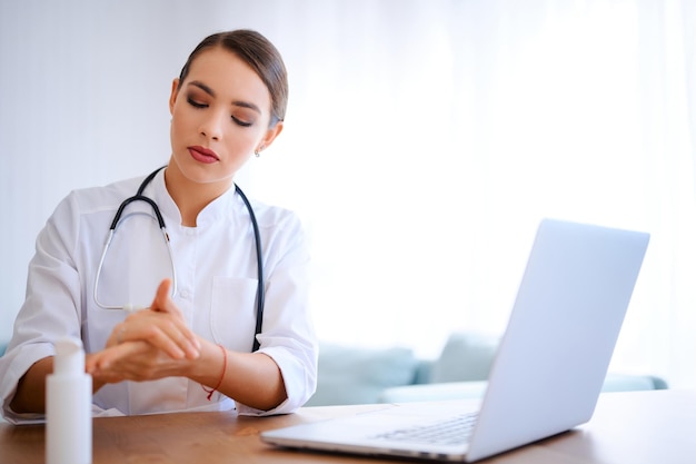 Young female doctor applies antiseptic gel before start working day Hospital worker cleaning hands using liquid alcoholic sanitizer