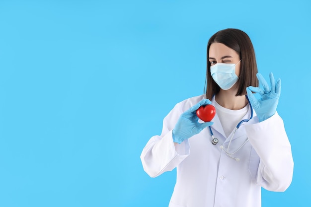 Giovane cardiologo medico femminile su sfondo blu