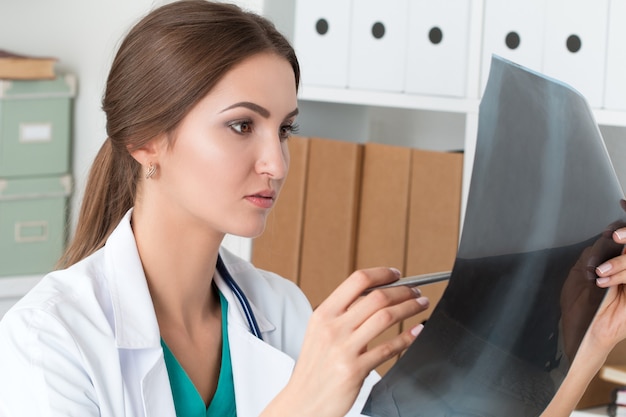 Young female doctor looking at lungs x ray image