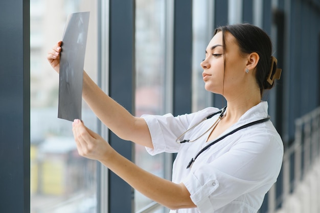 Young female doctor looking at the xray picture of lungs in hospital