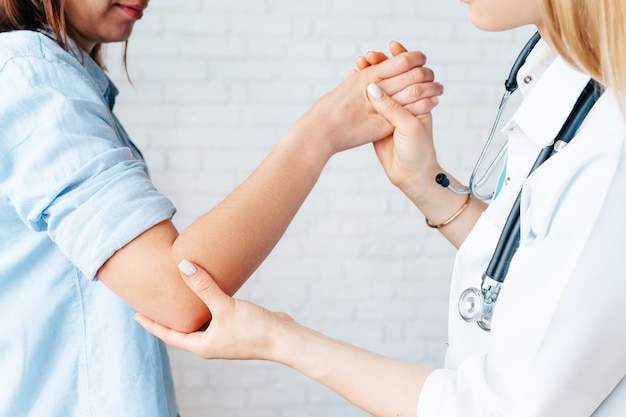 Young female doctor making an examination of patients hand and doing physical exercisesOrthopedist