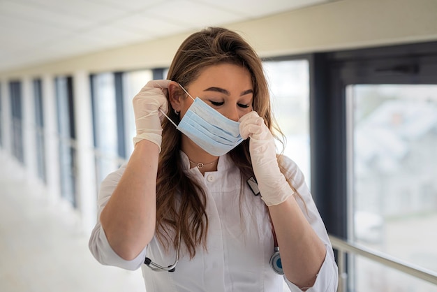 Giovane dottoressa o infermiera che mette una maschera per la protezione contro il coronavirus covid-19.