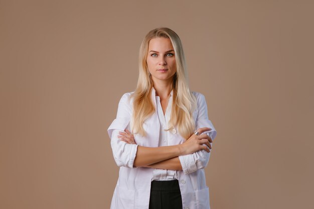 Young female doctor nutritionist smiles at beige wall