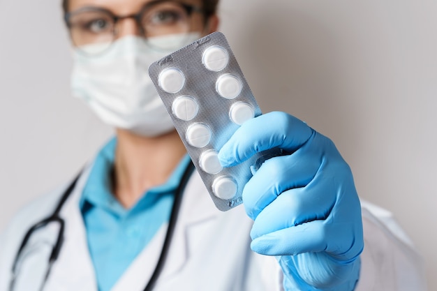 Young female doctor and pills in foil packaging