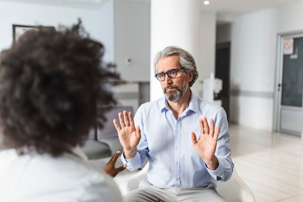 Young female doctor and senior man communicating in a waiting room at hospital.