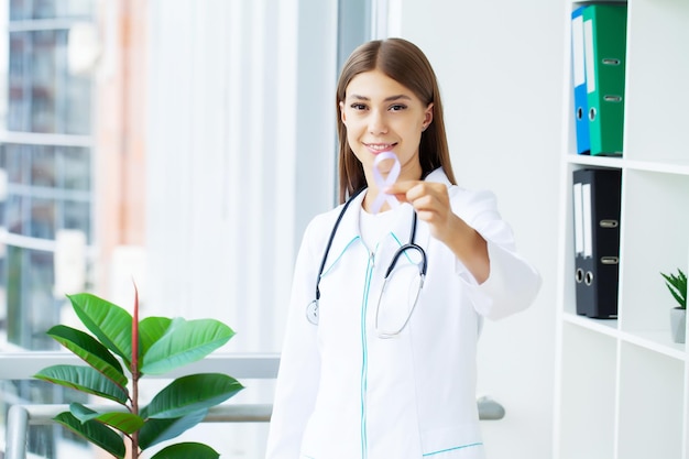 Young female doctor showing purple ribbon as a symbol to
awareness lse or alzheimer awareness symbol.