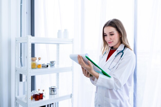 Young female doctor therapeutic advising with positive emotions hold clipboard up with smiley face very good on wooden table in Hospital background