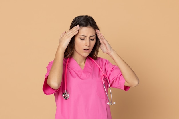 茶色の壁に身振りで示すピンクの制服を着た若い女性医師