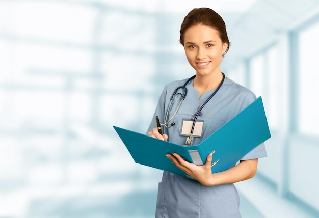 Young female doctor with stethoscope on blurred hospital background
