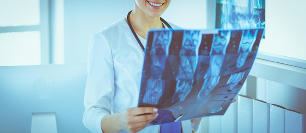 Young female doctor with stethoscope examining Xray at doctor's office