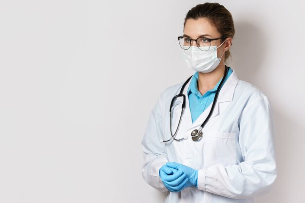 Young female doctor with a stethoscope on gray wall