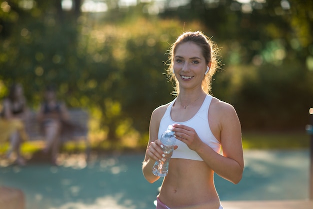 Young female drinking water after training on the outdoor playground