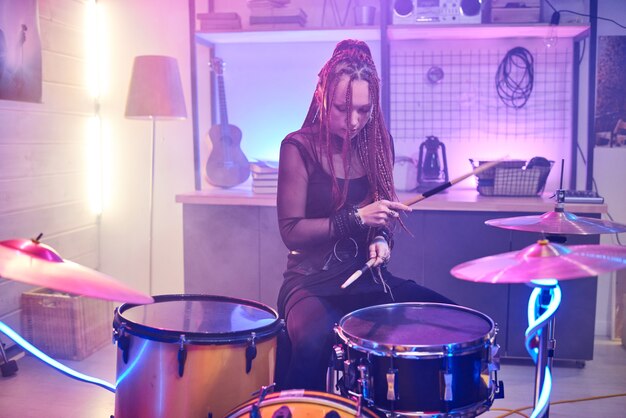 Молодая барабанщица играет на барабанах во время ее выступления