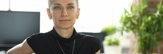 Young female employee is sitting at a table in the office leaning her hand on a chair