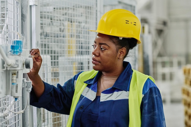 Giovane ingegnere femminile che accende apparecchiature industriali prima del lavoro