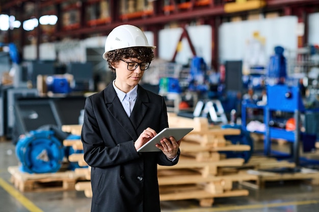 Young female engineer with tablet scrolling through online information