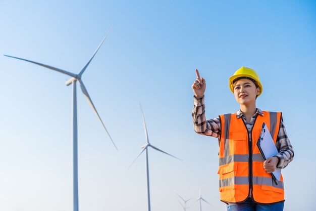 Young female engineer working  against wind turbine farm