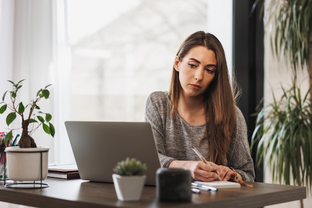 Young female entrepreneur looking thoughtful while working from her home office.