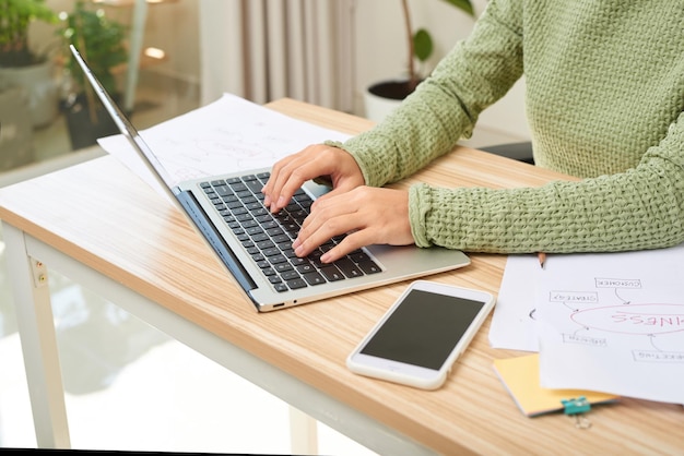 Young female entrepreneur working sitting at a desk typing on her laptop in a home office