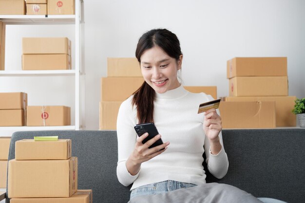 Young female entrepreneur working with laptop computer and using credit card at home