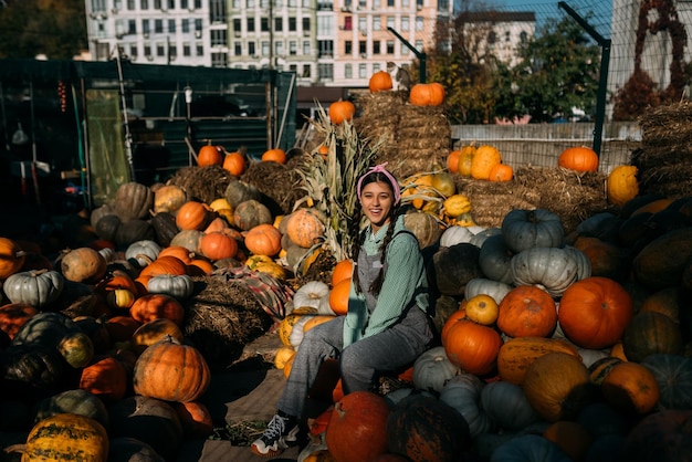 Young female farmer sits among a large number of pumpkins