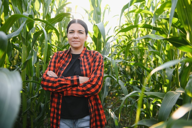 畑で働き、植物の農業と健康的な生活の概念をチェックする若い女性農家