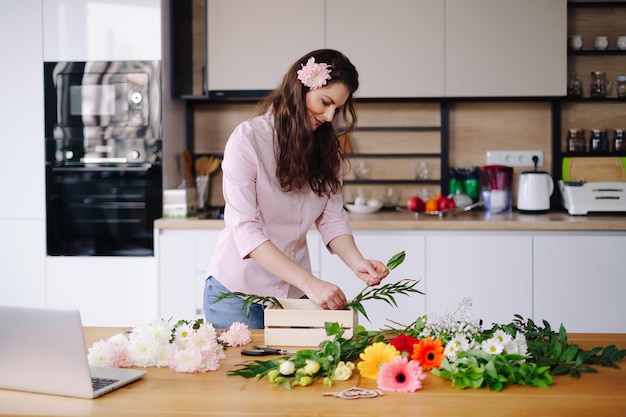 若い女性の花屋は、カメラで花の組成物のデザインのビデオチュートリアルを記録します女性のインテリアデザイナーは、カメラでvlogを撮影し、手作りの家の花の装飾をアレンジします