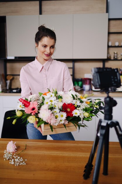 Young female florist record video tutorial of floral compositions design on camera woman interior designer shoot vlog on camera arrange handmade house flower decorations