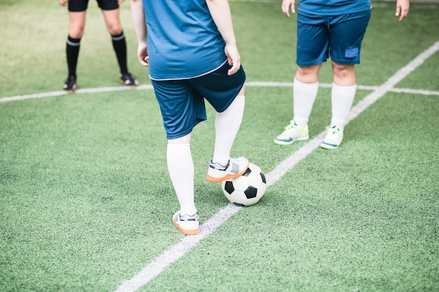 필드에 다른 여자 앞에 서있는 동안 축구 공에 오른발을 유지하는 젊은 여성 축구 선수